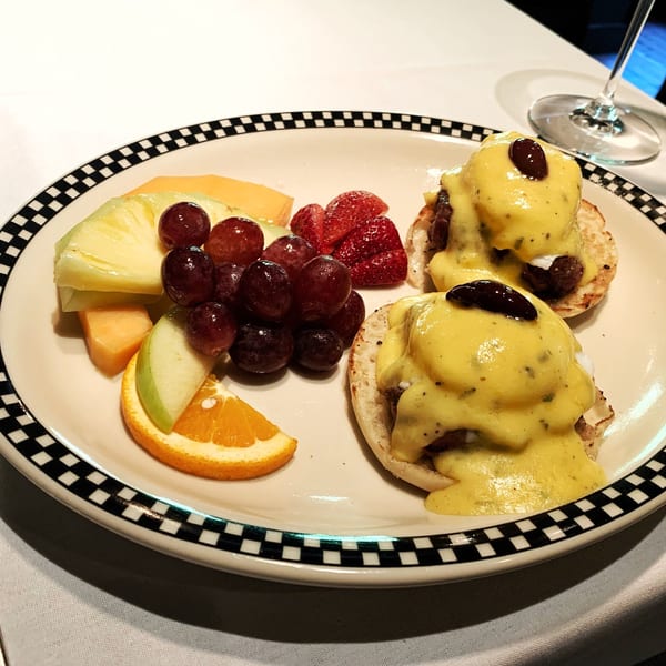 Polo Grill's Eggs Benedict with fruit, including grapes, pineapple, melon, strawberries, and orange slices.