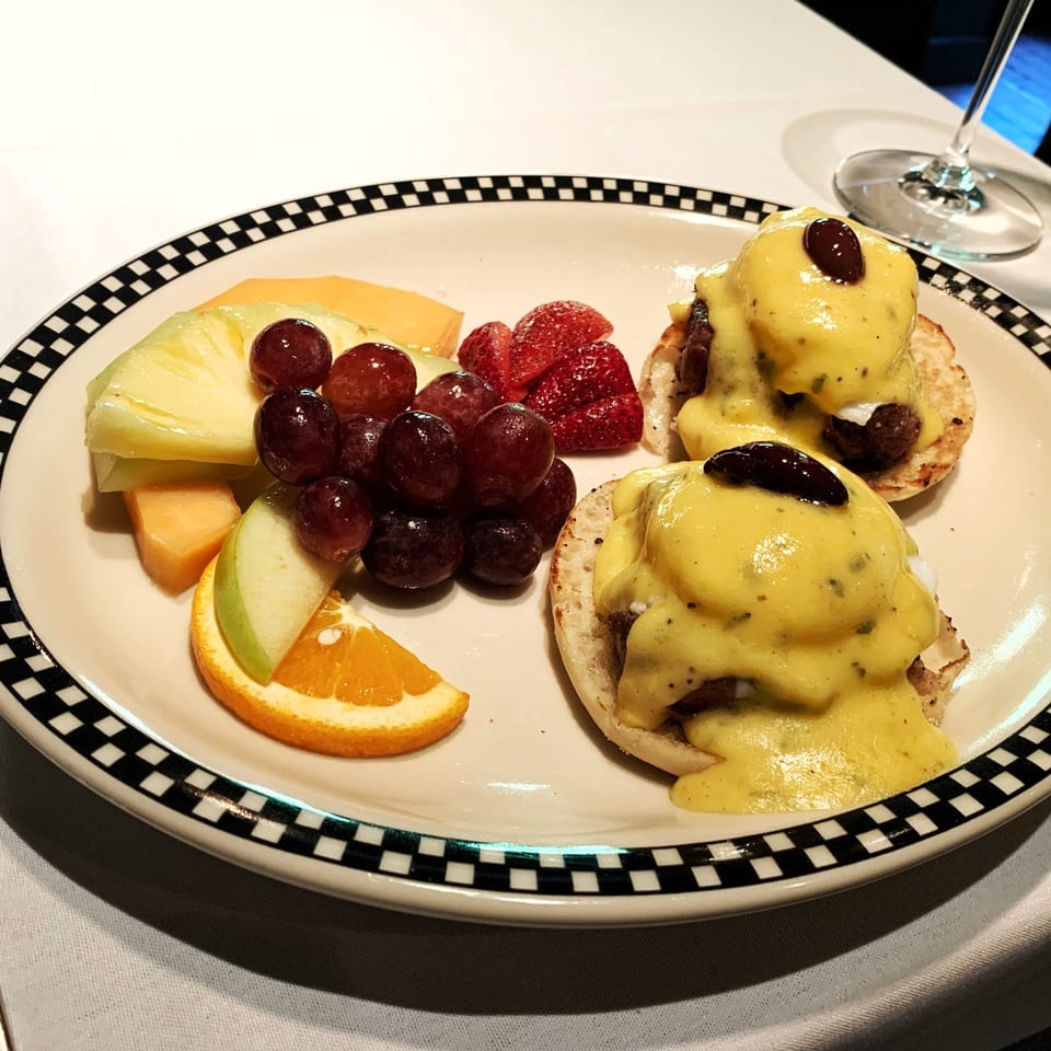 Polo Grill's Eggs Benedict with fruit, including grapes, pineapple, melon, strawberries, and orange slices.