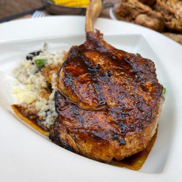 Polo Grill's grilled pork chop with a rich glaze, served with risotto on a white plate.